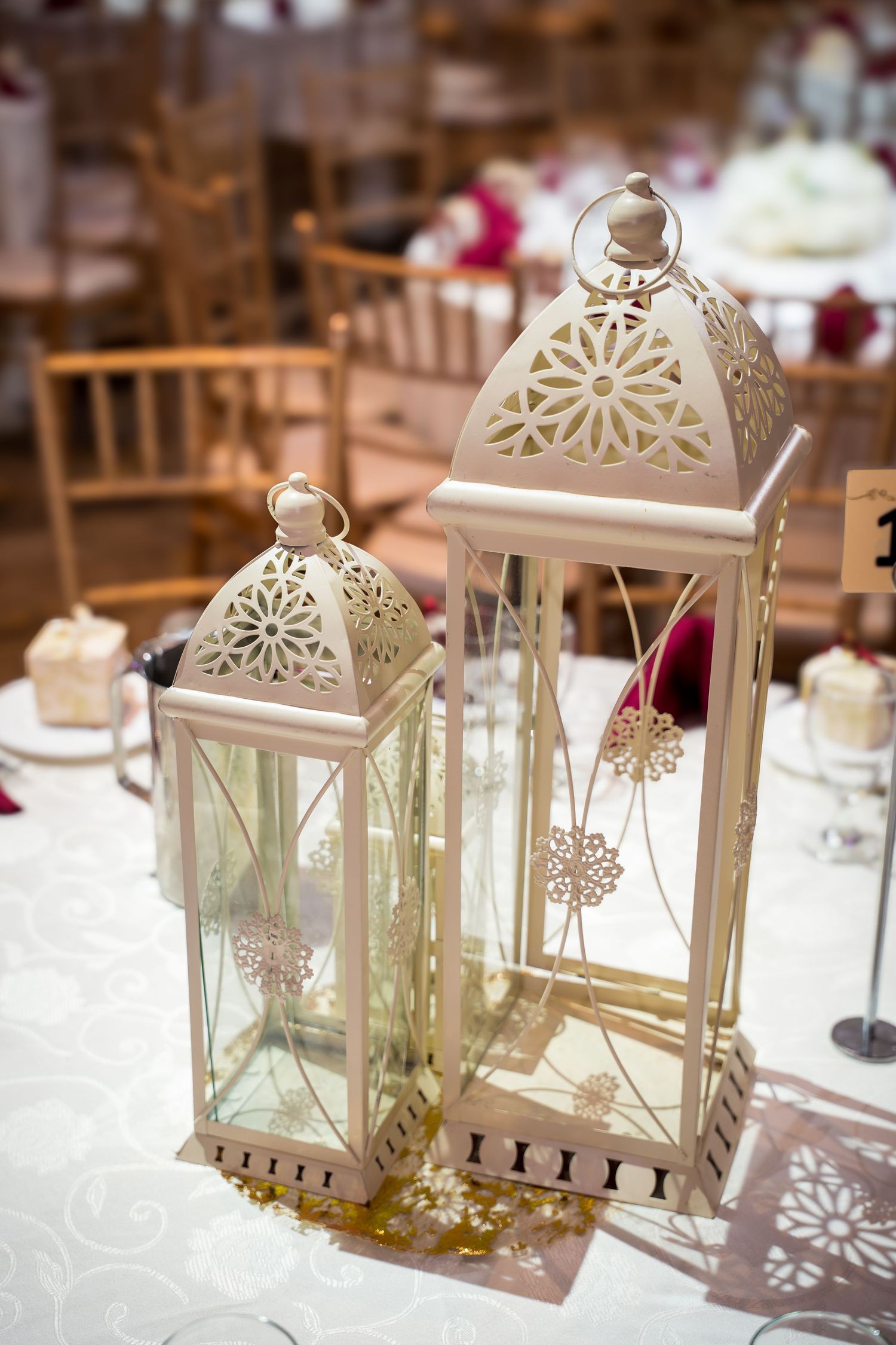 White decorative lanterns with snowflake patterns arranged on a wedding reception table.