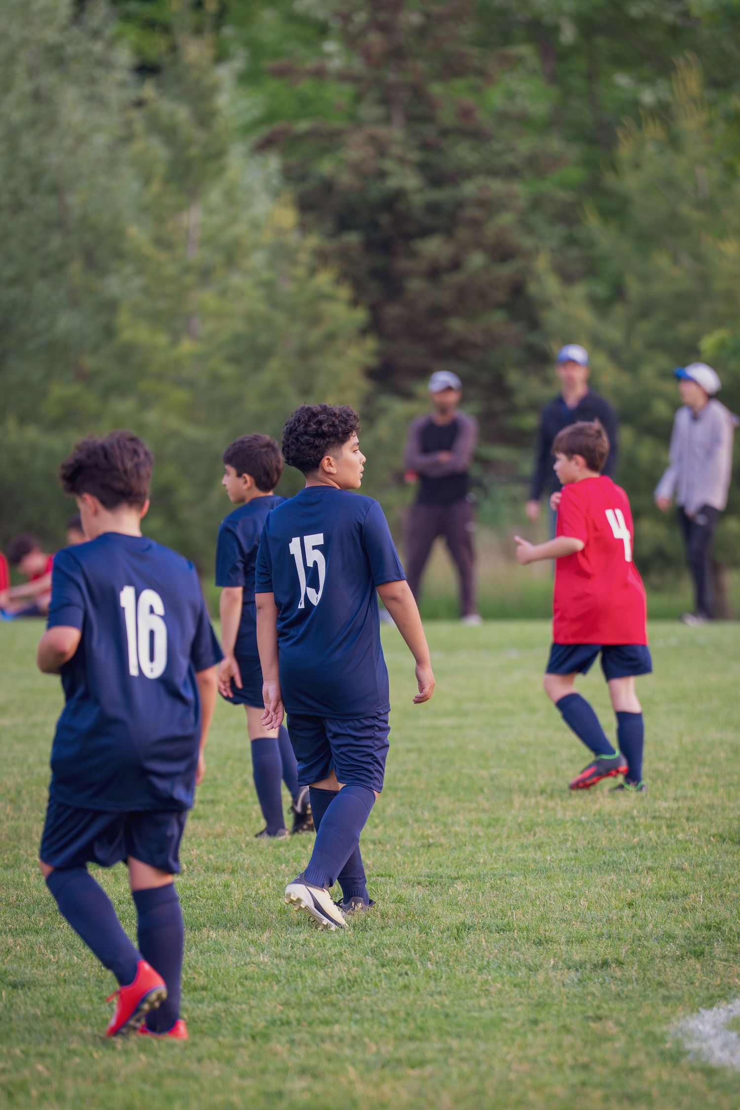 Soccer players in navy blue uniforms stretch and warm up on a grassy field during practice session.