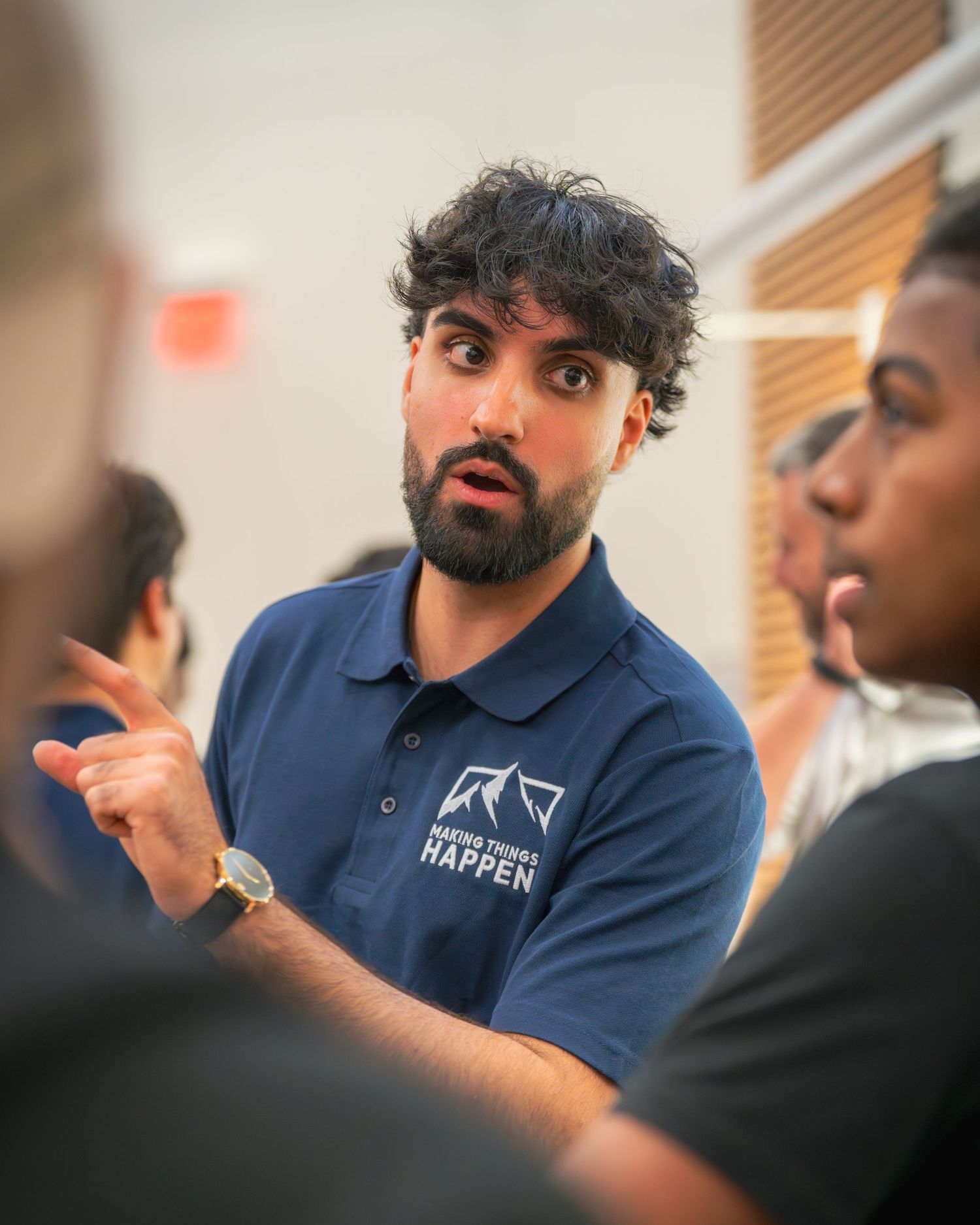Presenter in navy branded polo gestures while speaking to audience.