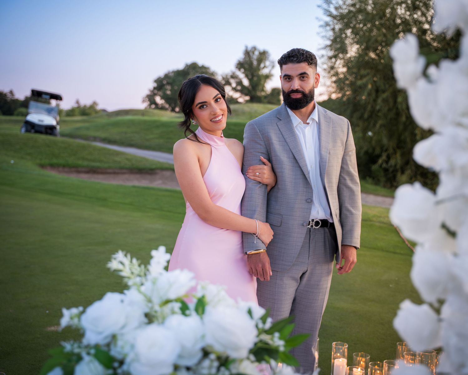 Elegant outdoor portrait session with white flowers and candlelight on a golf course.