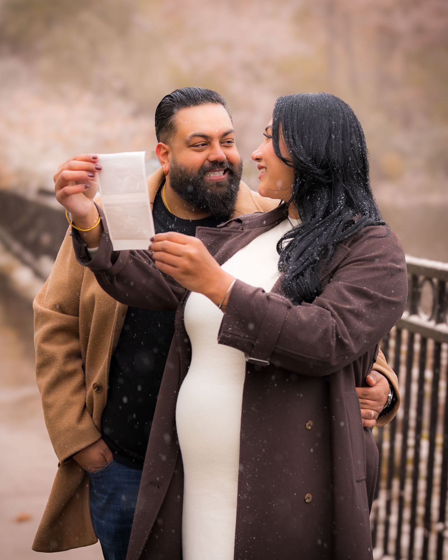 A couple shares a joyful moment during a winter proposal photoshoot.