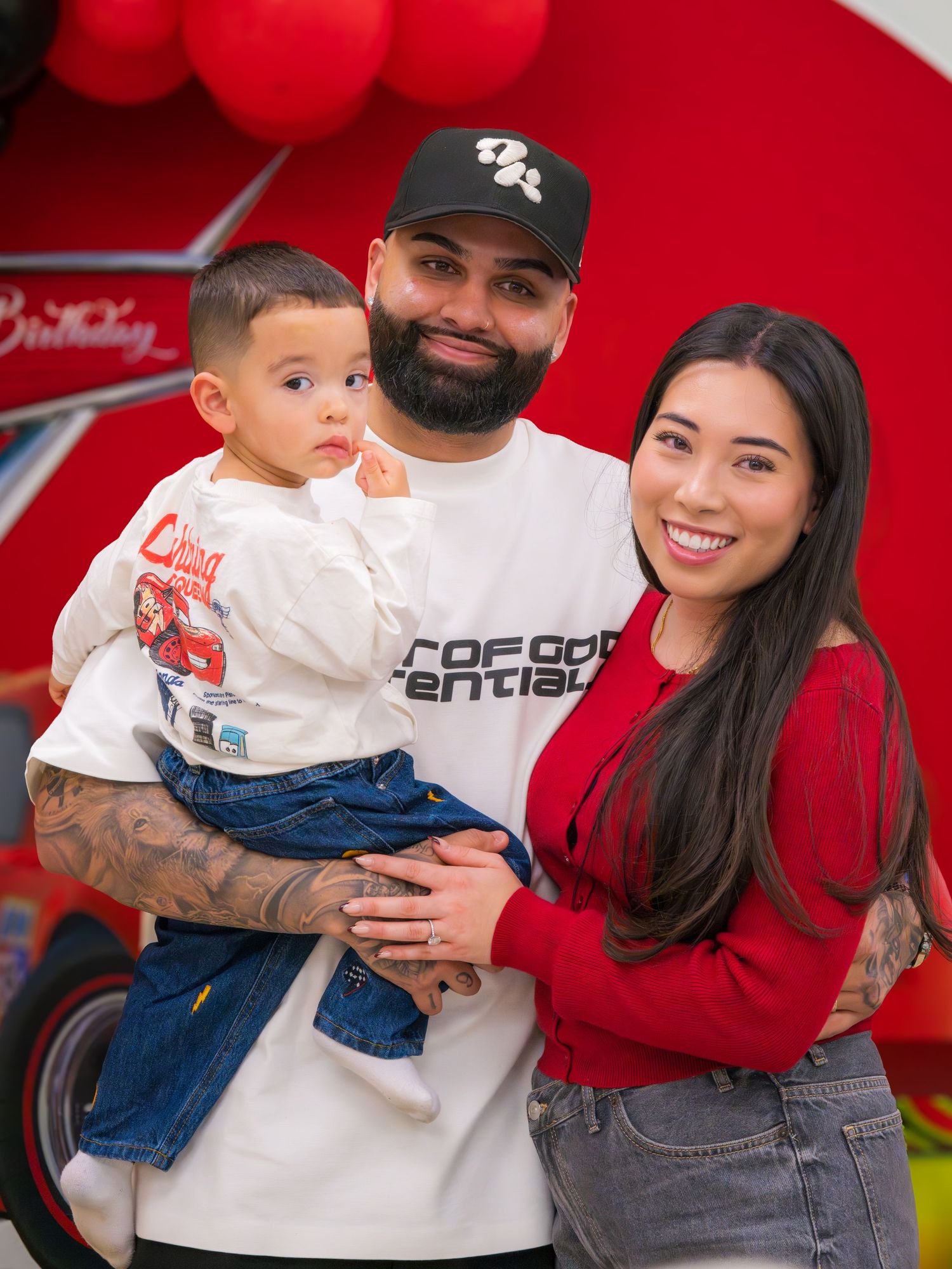Family portrait of parents with toddler son at a Cars-themed birthday party.