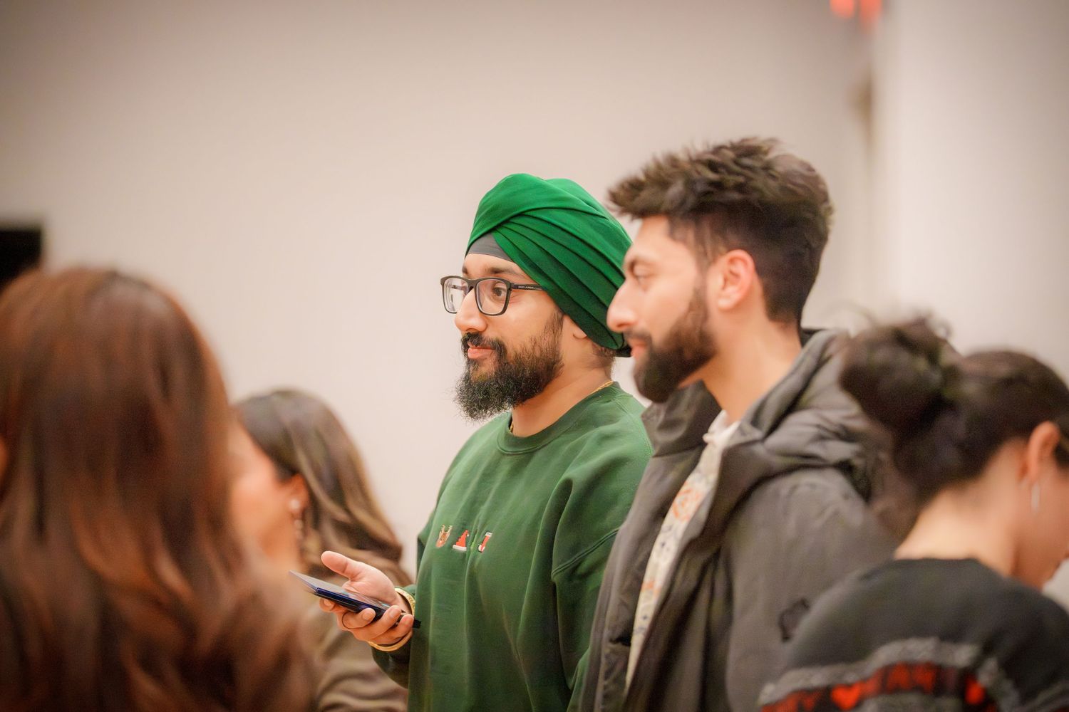 Guests mingling at an indoor social event with someone wearing a green beanie.