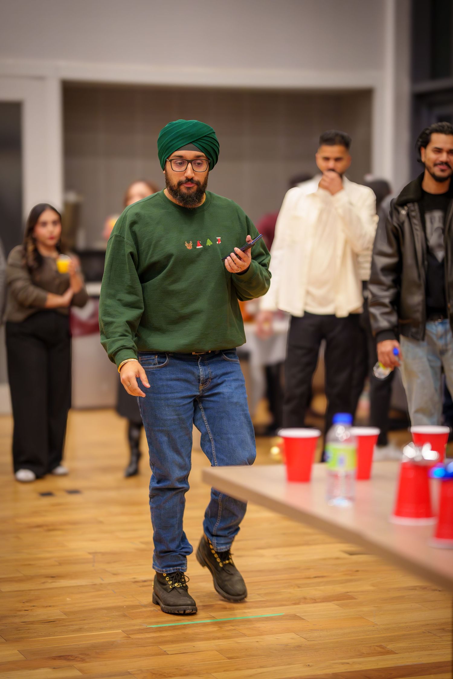 People playing a fun party game on a hardwood floor with red cups.