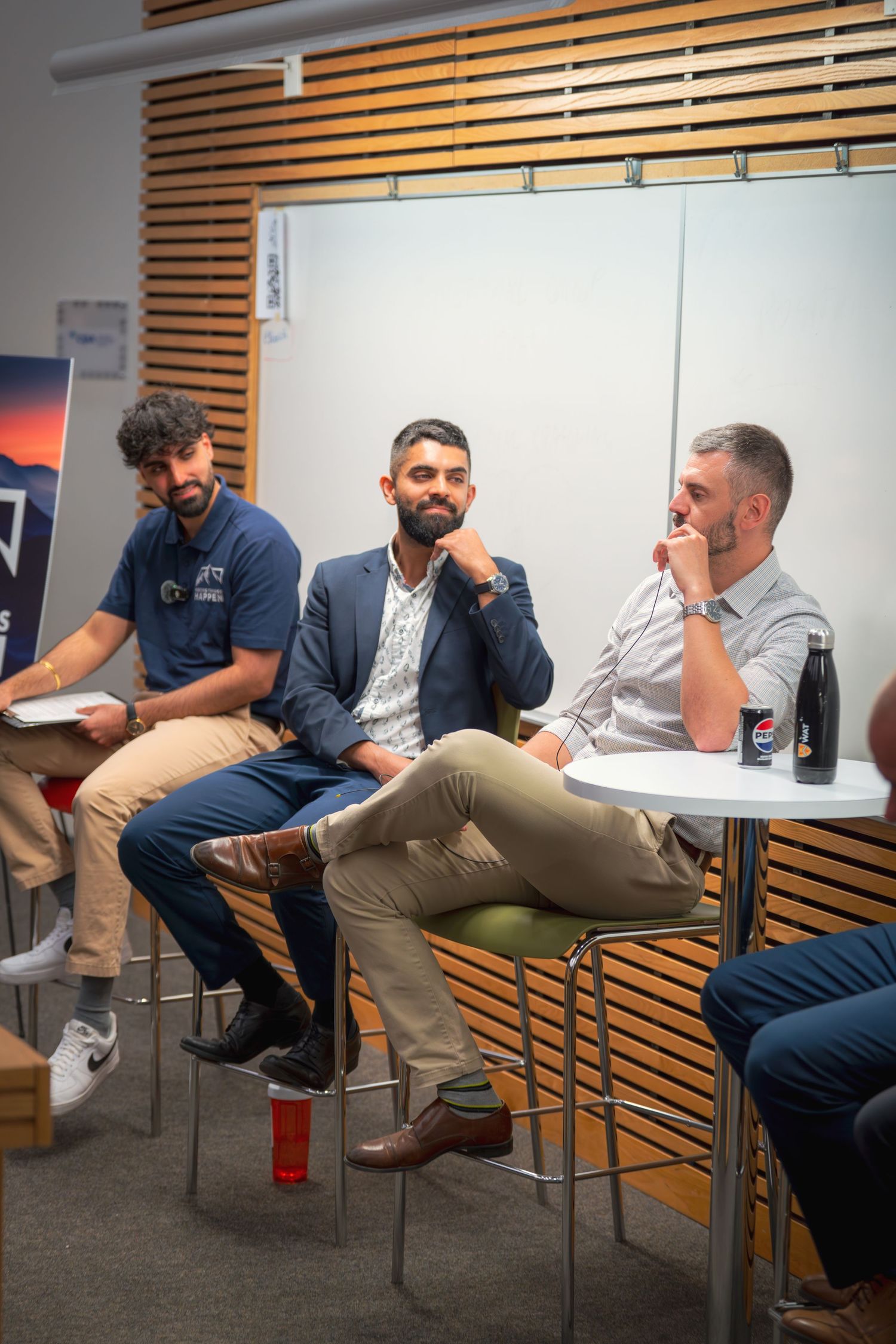 Meeting participants seated in chairs engaging in conversation in a conference room.