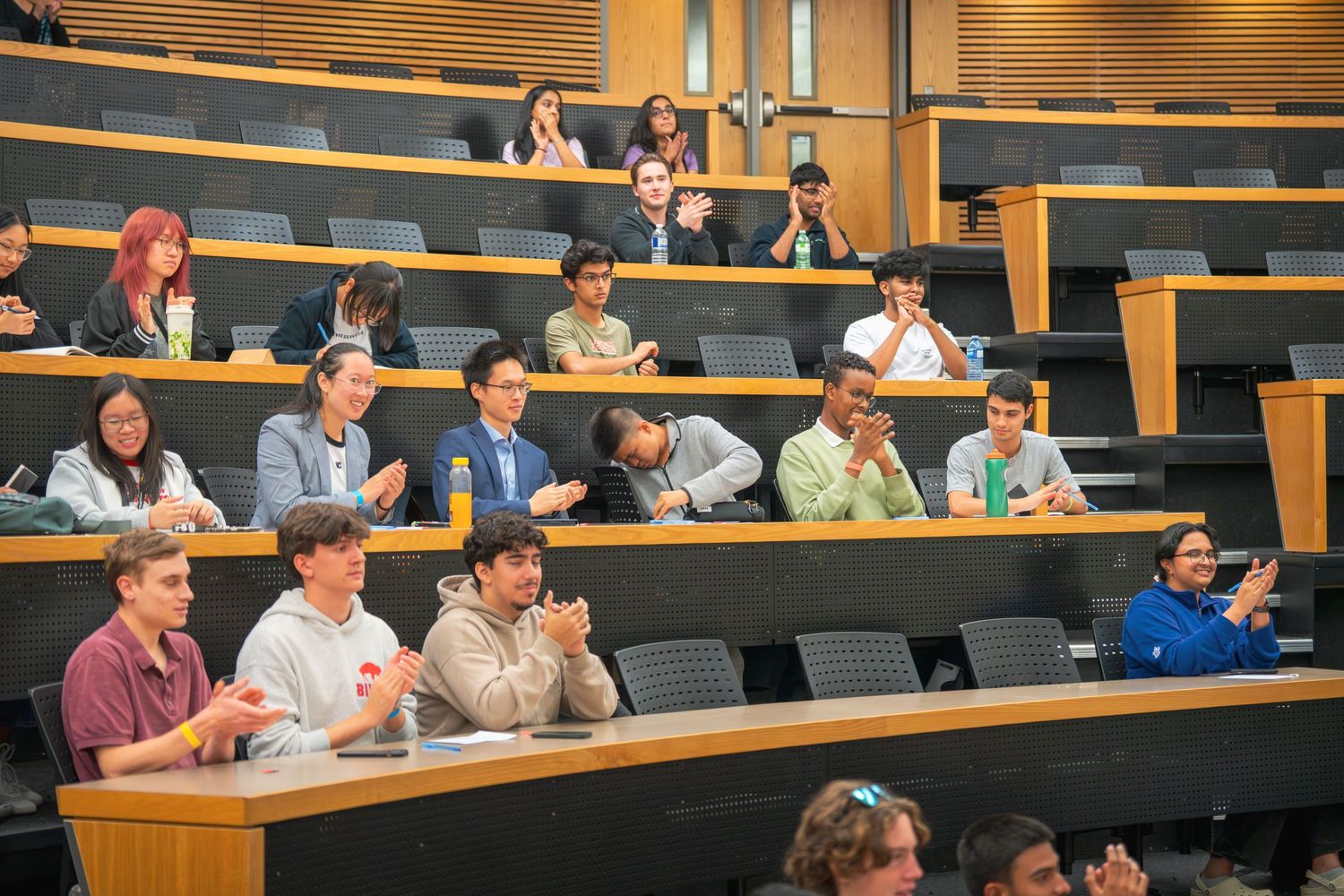 Audience members seated in tiered rows listen attentively during a presentation.