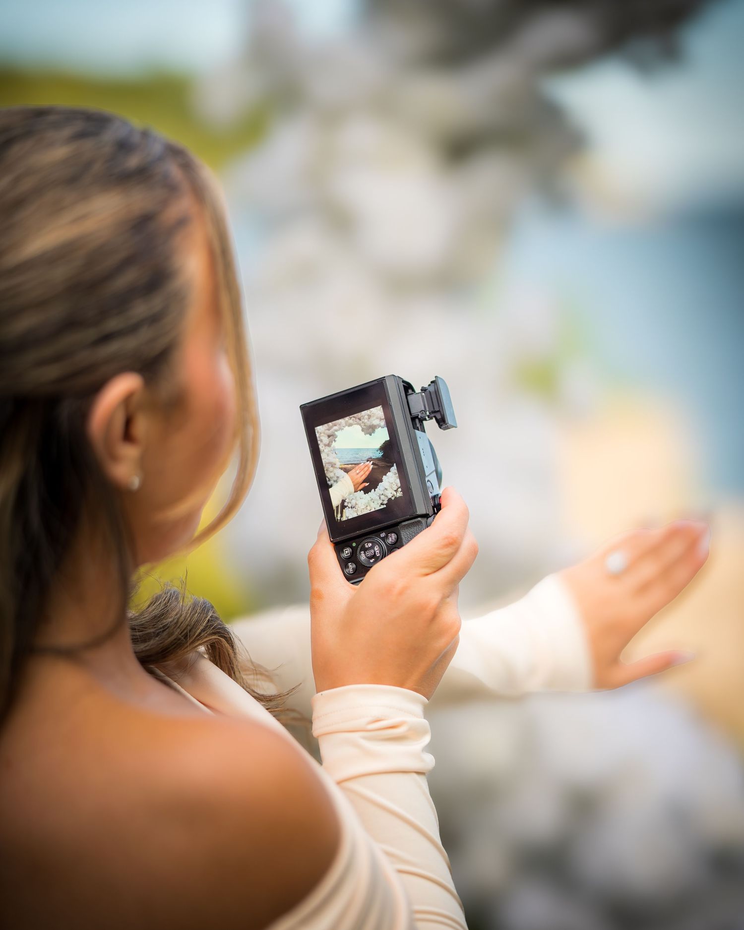 Someone holds a small digital camera while taking photos outdoors.