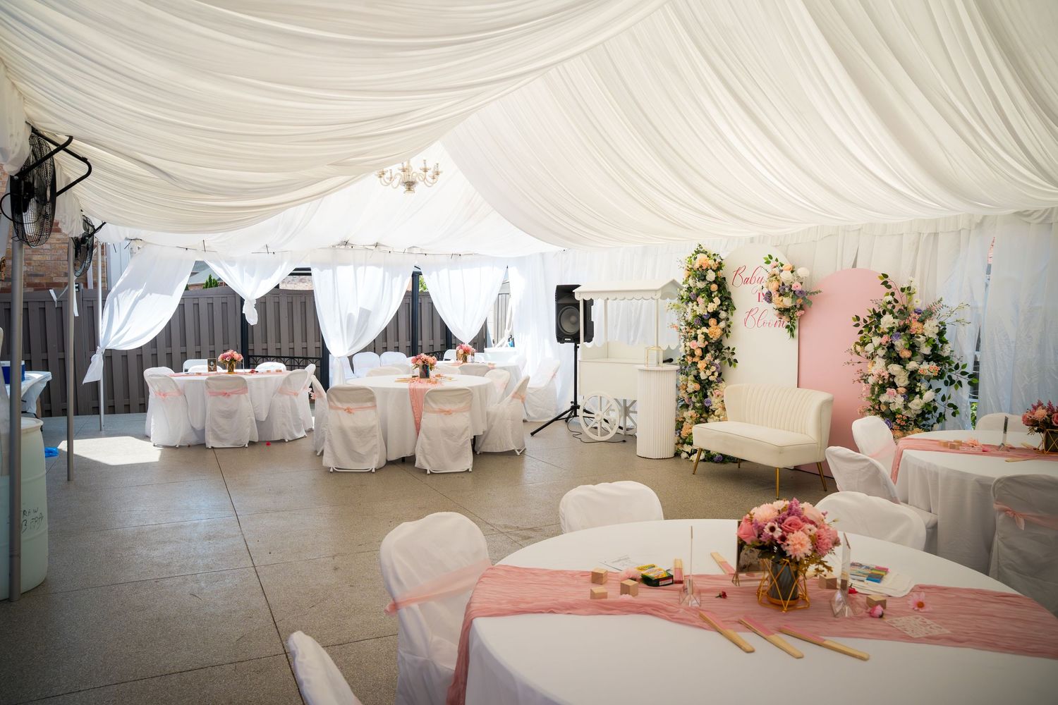 White draped wedding tent interior with floral arrangements and reception seating.