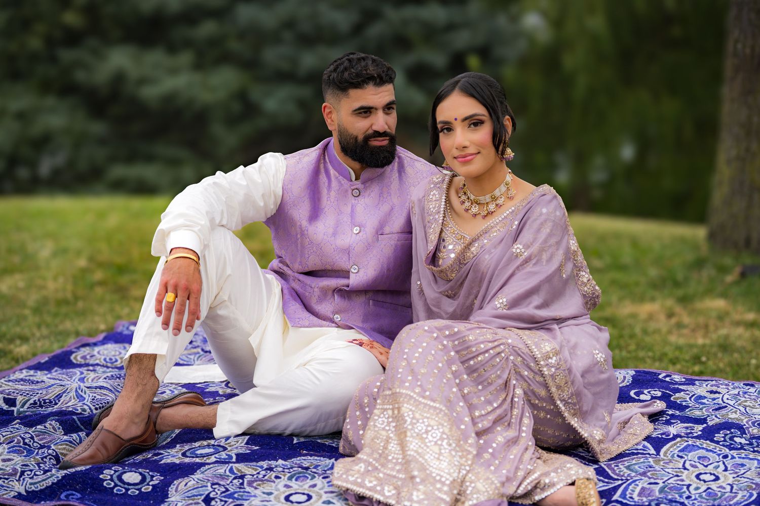 Couple shares tender moments during outdoor photoshoot on blue patterned blanket.