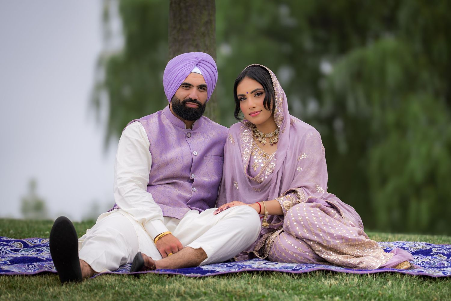 A couple shares an intimate moment while sitting on a blanket during their outdoor engagement session.