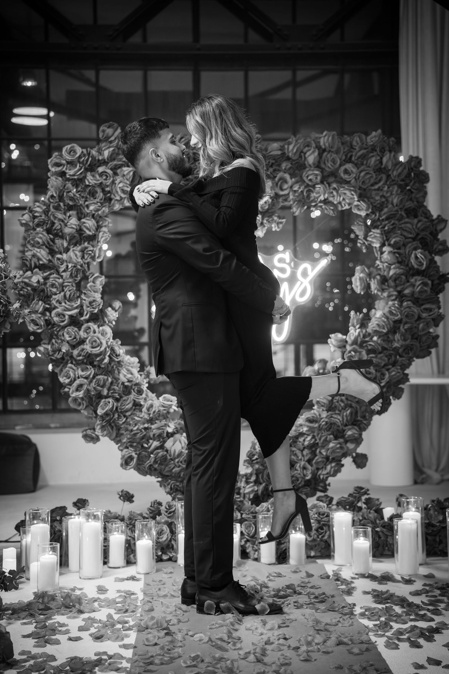 Intimate proposal moment surrounded by candles and floral arrangements.