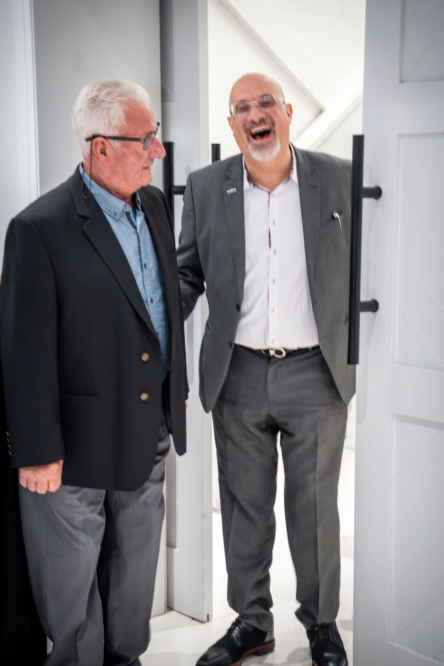 Business professionals having an animated conversation in a white hallway.