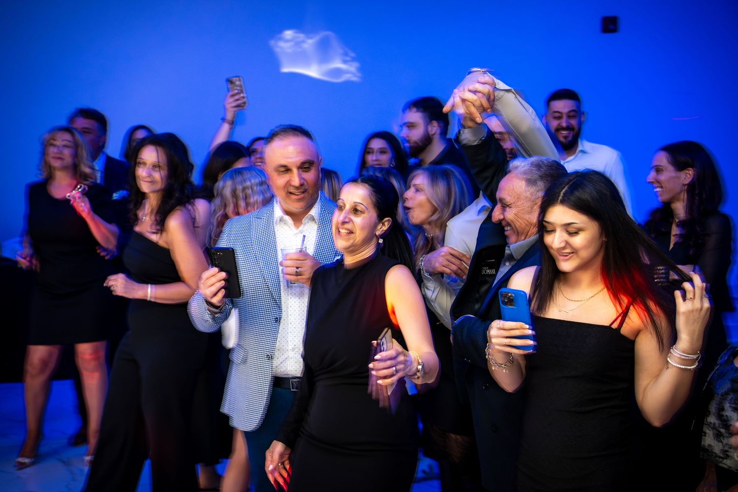 Lively dance floor scene with people enjoying themselves under blue ambient lighting.