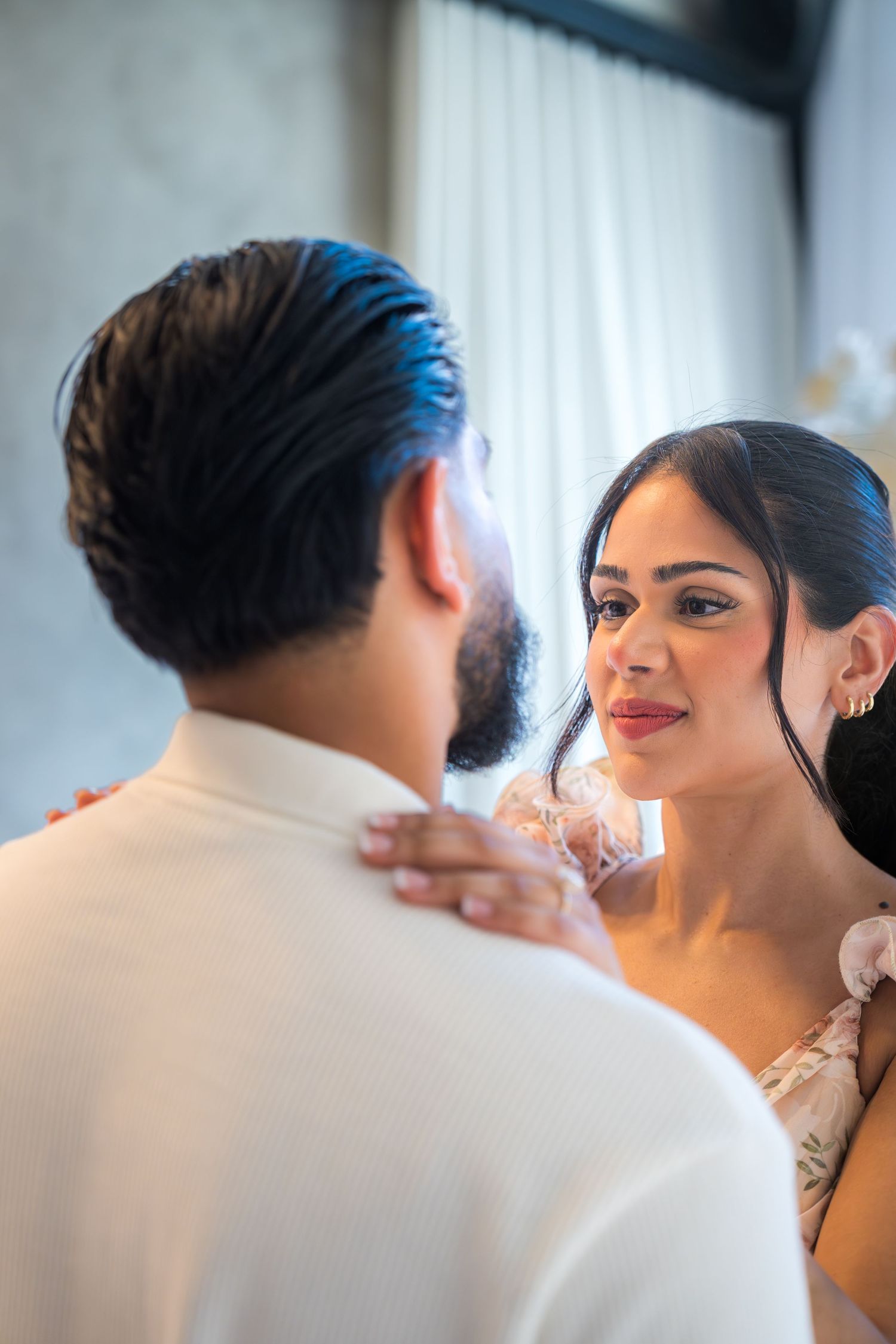 Emotional bride-to-be gazing at partner during romantic marriage proposal in elegant white venue.
