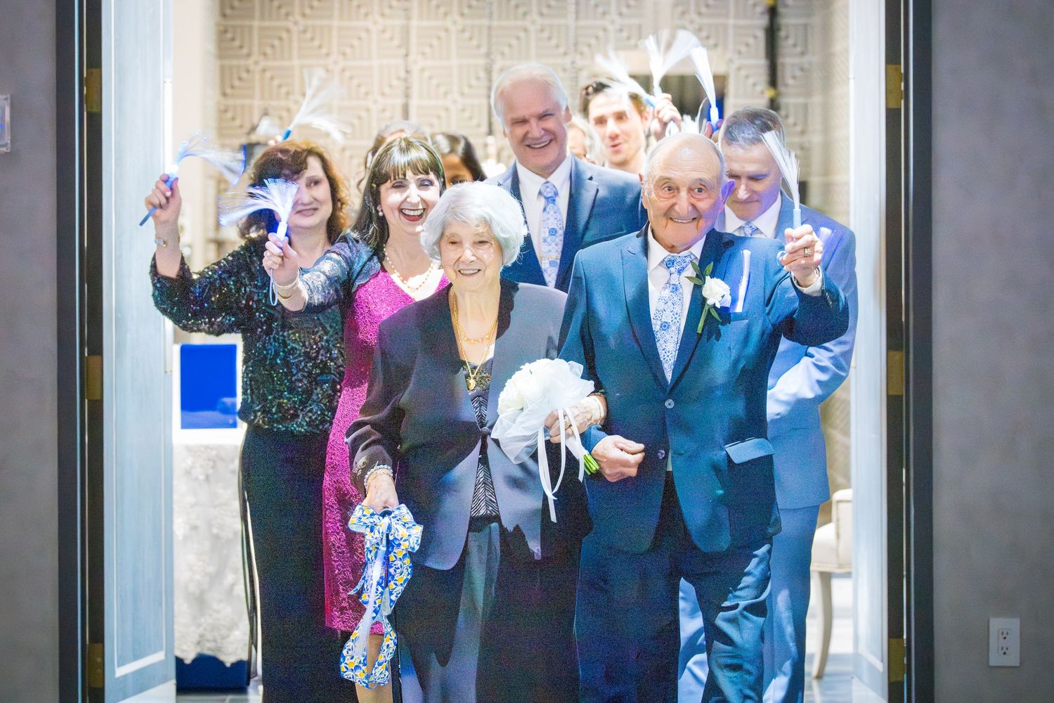 Group of joyful guests celebrating with streamers as couple makes grand entrance at anniversary party.