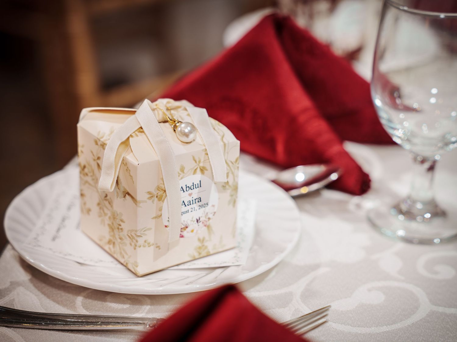 Elegant wedding favor boxes in cream and burgundy colors arranged on formal table settings.