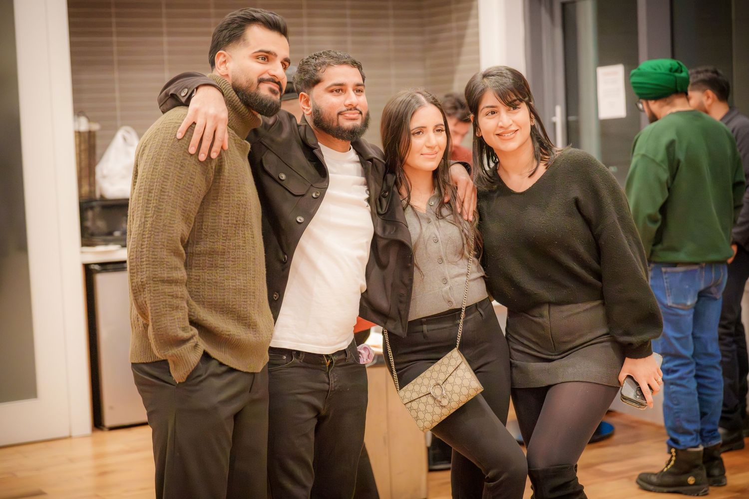 Indoor social gathering with people posing and interacting in a modern space.
