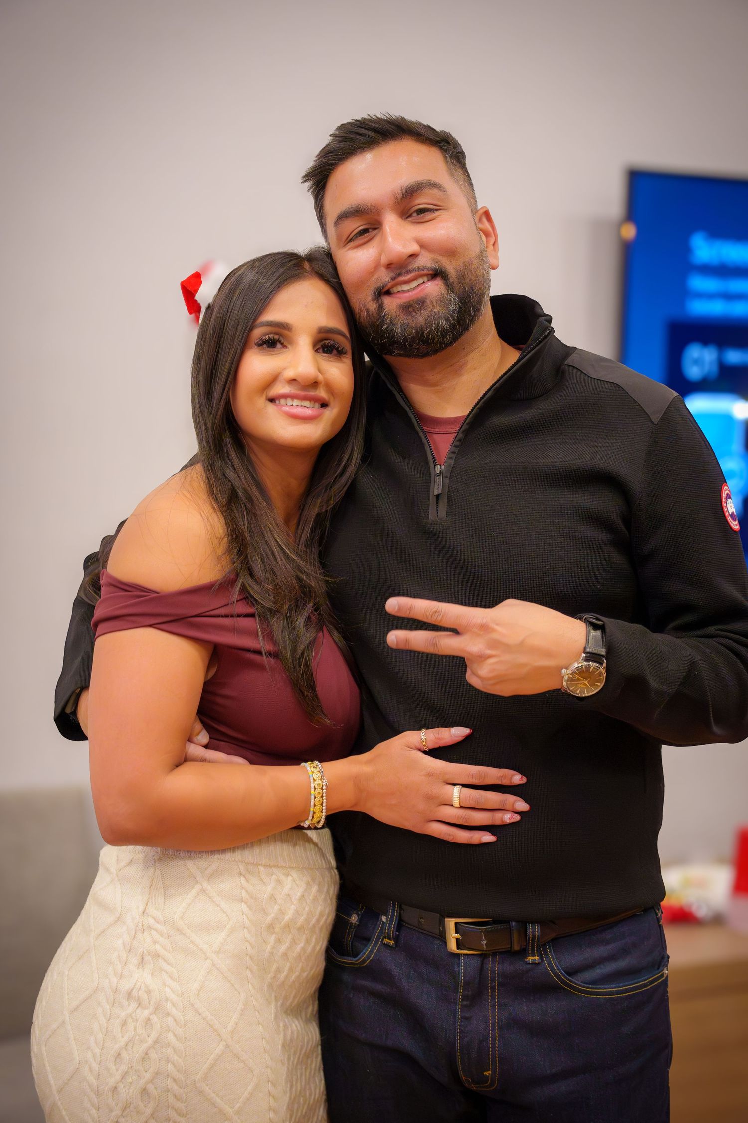 Two people posing together at a party with festive lighting and decorations in the background.