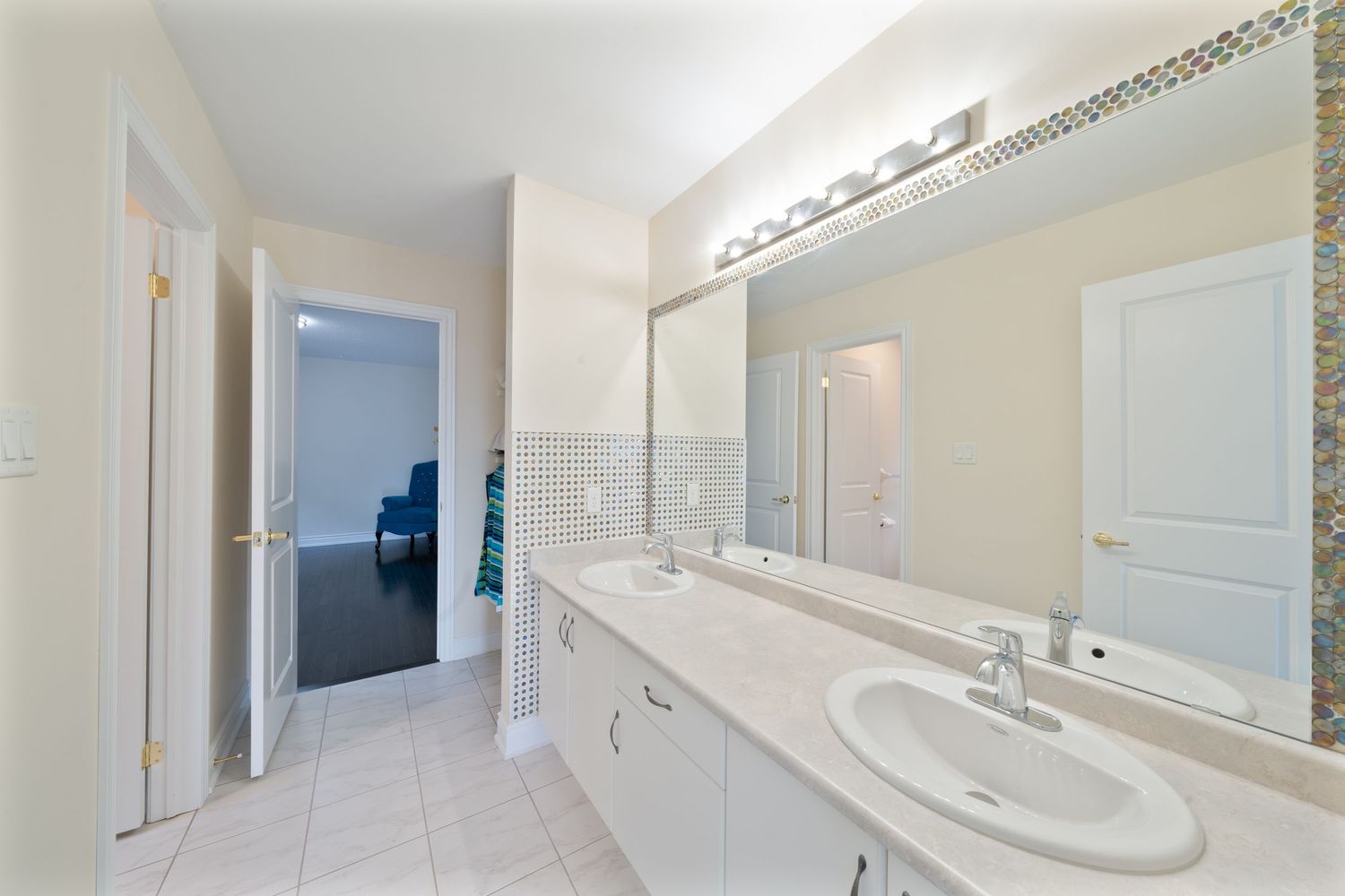 A modern white bathroom with a pedestal sink, mirror, and white wainscoting features a clean, minimalist design.