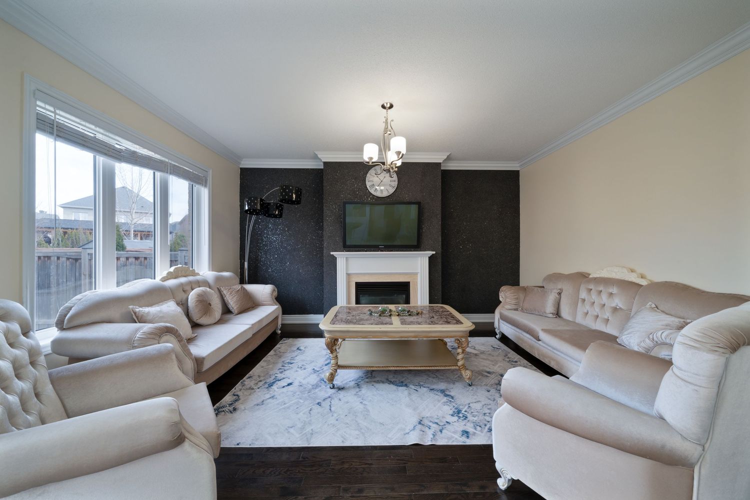 Modern living room interior with white sectional sofa, glass coffee table, and contemporary pendant lighting.