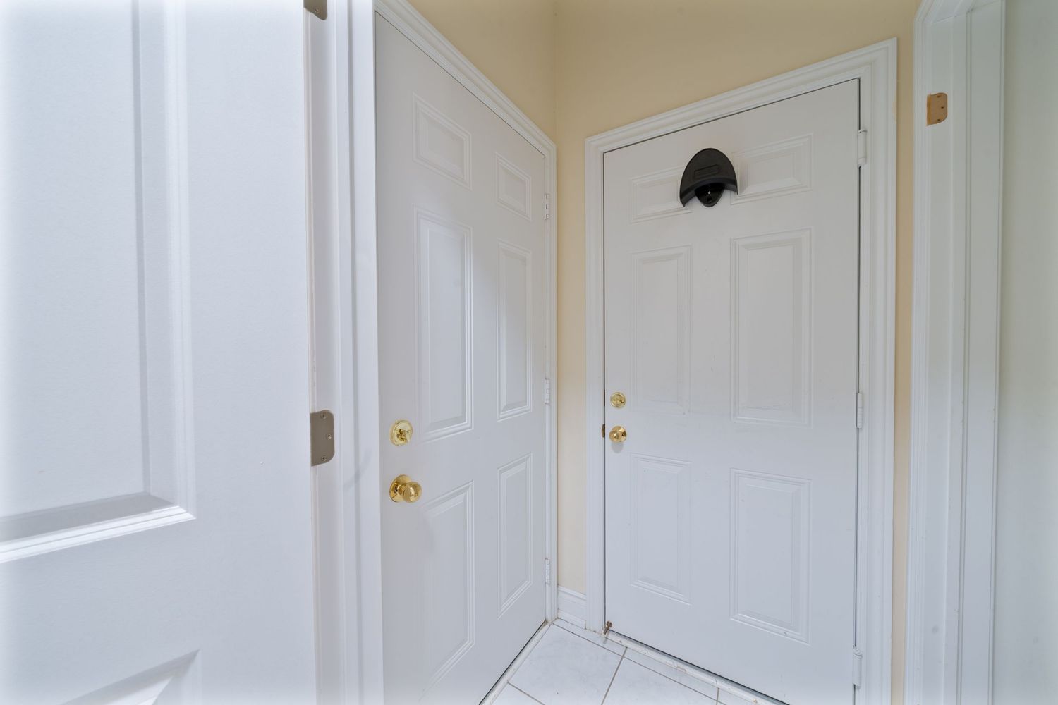 White interior doors with brass handles line a hallway with beige walls and crown molding.