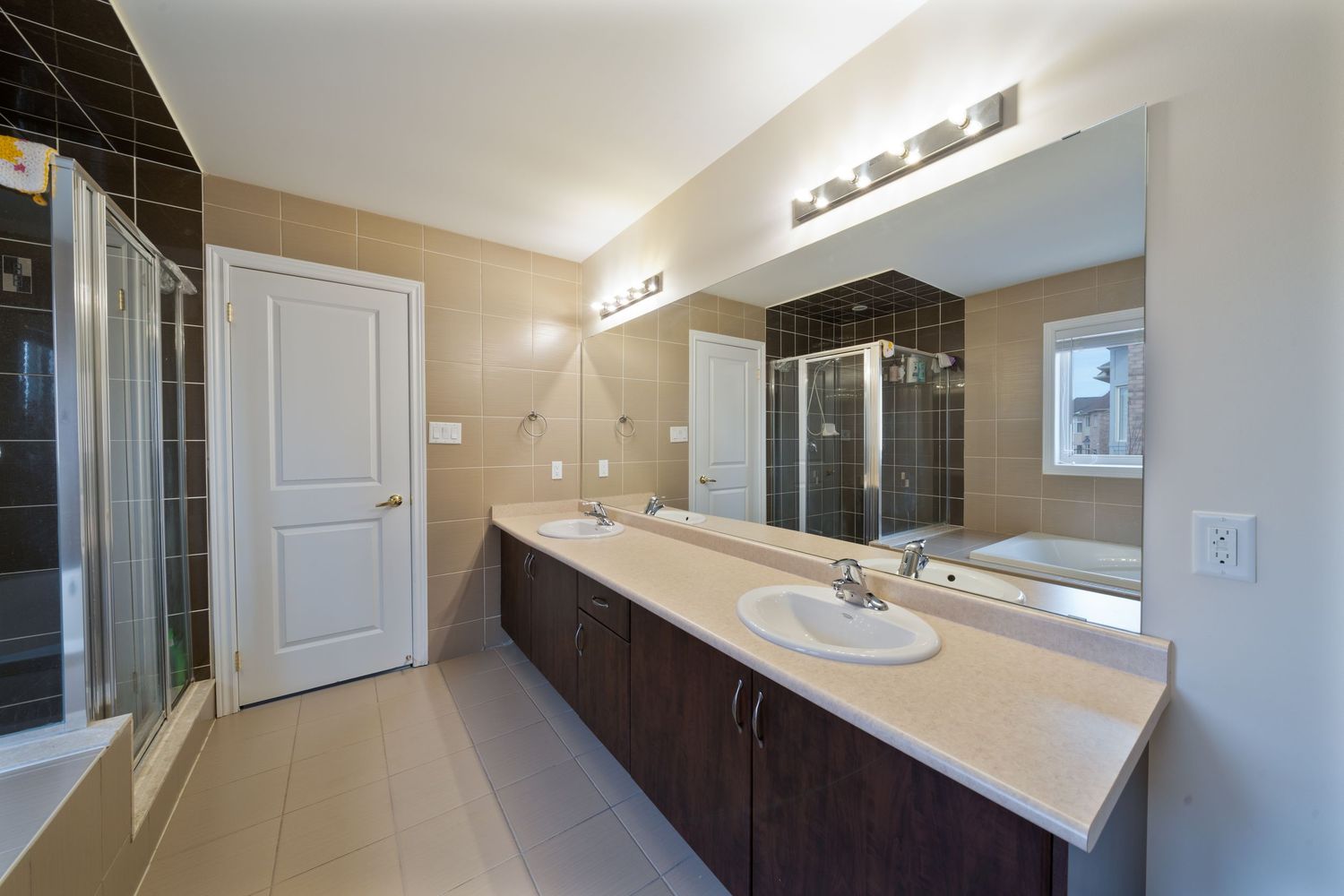 Modern bathroom interior with white quartz countertop, dark wood cabinets and chrome fixtures under vanity lighting.