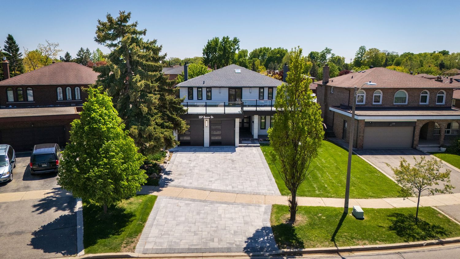 Aerial panoramic view of a suburban neighborhood with modern homes and well-maintained landscaping on a sunny day.
