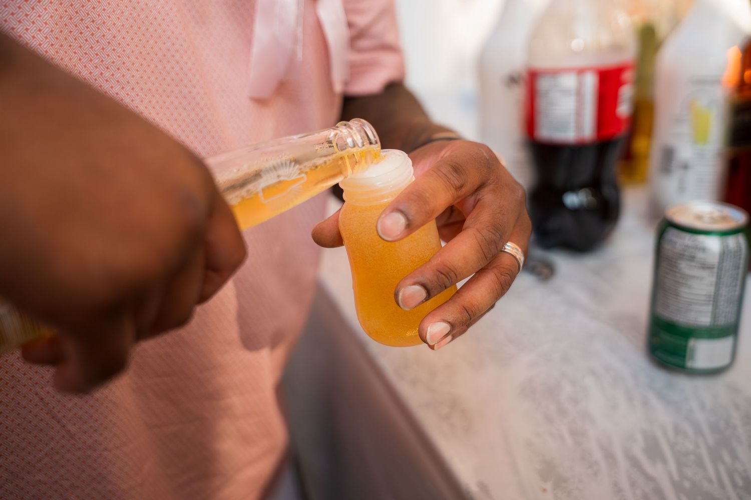 Hands holding beverages against a pink textured background.