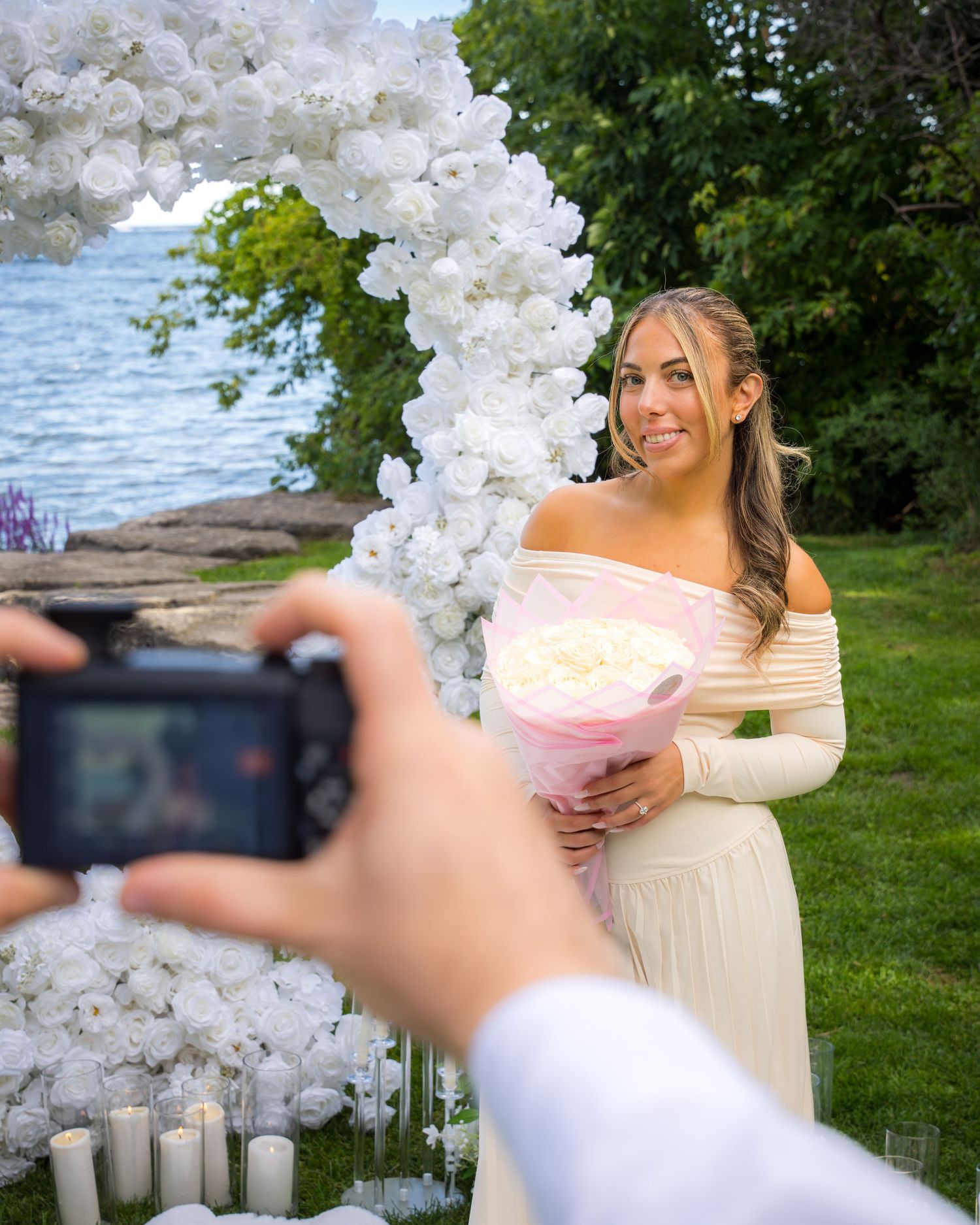 Wedding photography session with white balloon arch and pink bouquet by the water.