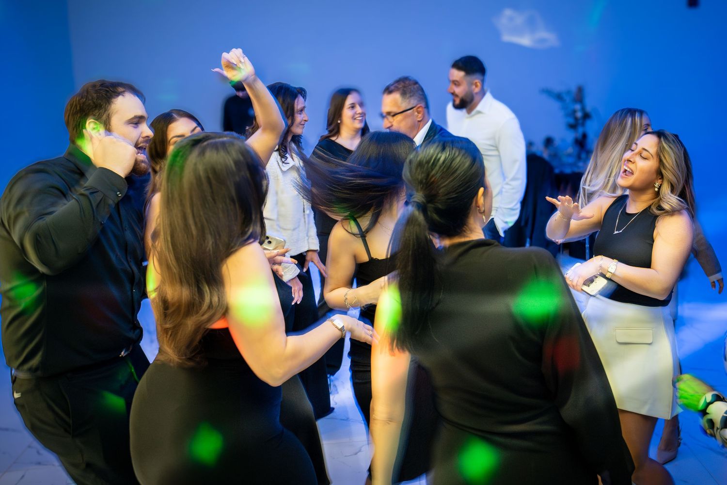 Energetic group dancing and celebrating at a social gathering with atmospheric lighting.