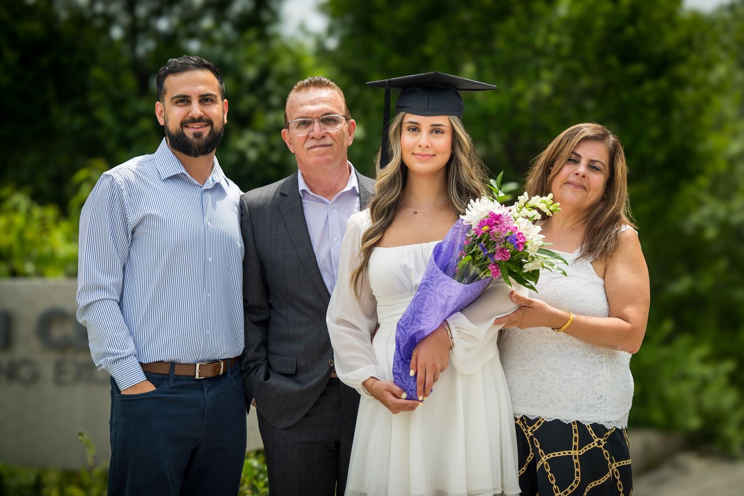Group graduation photo with graduates and family members outdoors.
