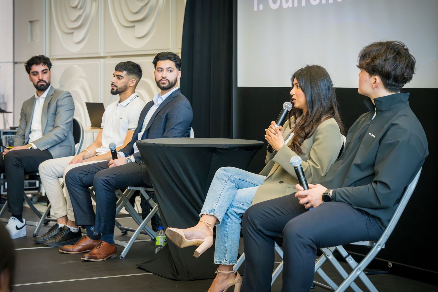 Business professionals engaged in conversation during panel event with modern stage setup.