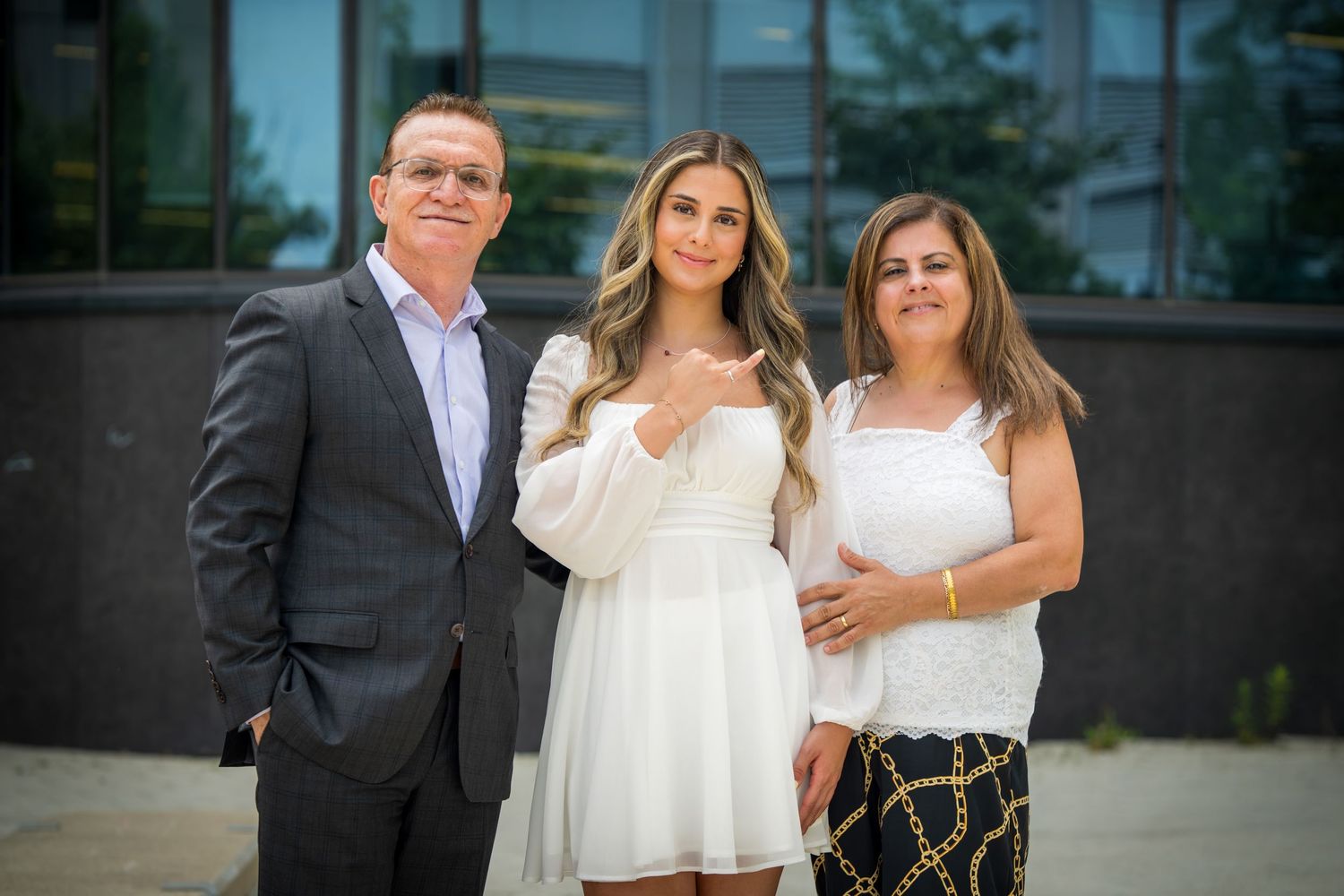 Family group stands together on stone pavement near glass building.