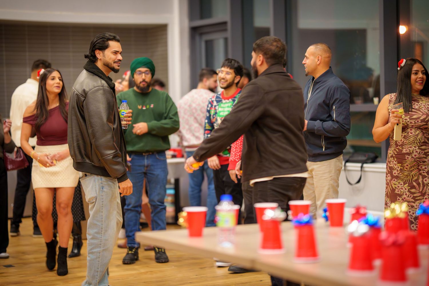 People gathered around red cups in indoor space during social event.