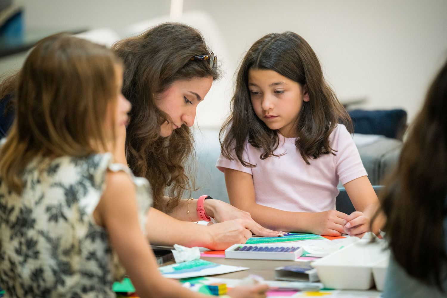 Art instructor guides young student through colorful paper collage craft activity.