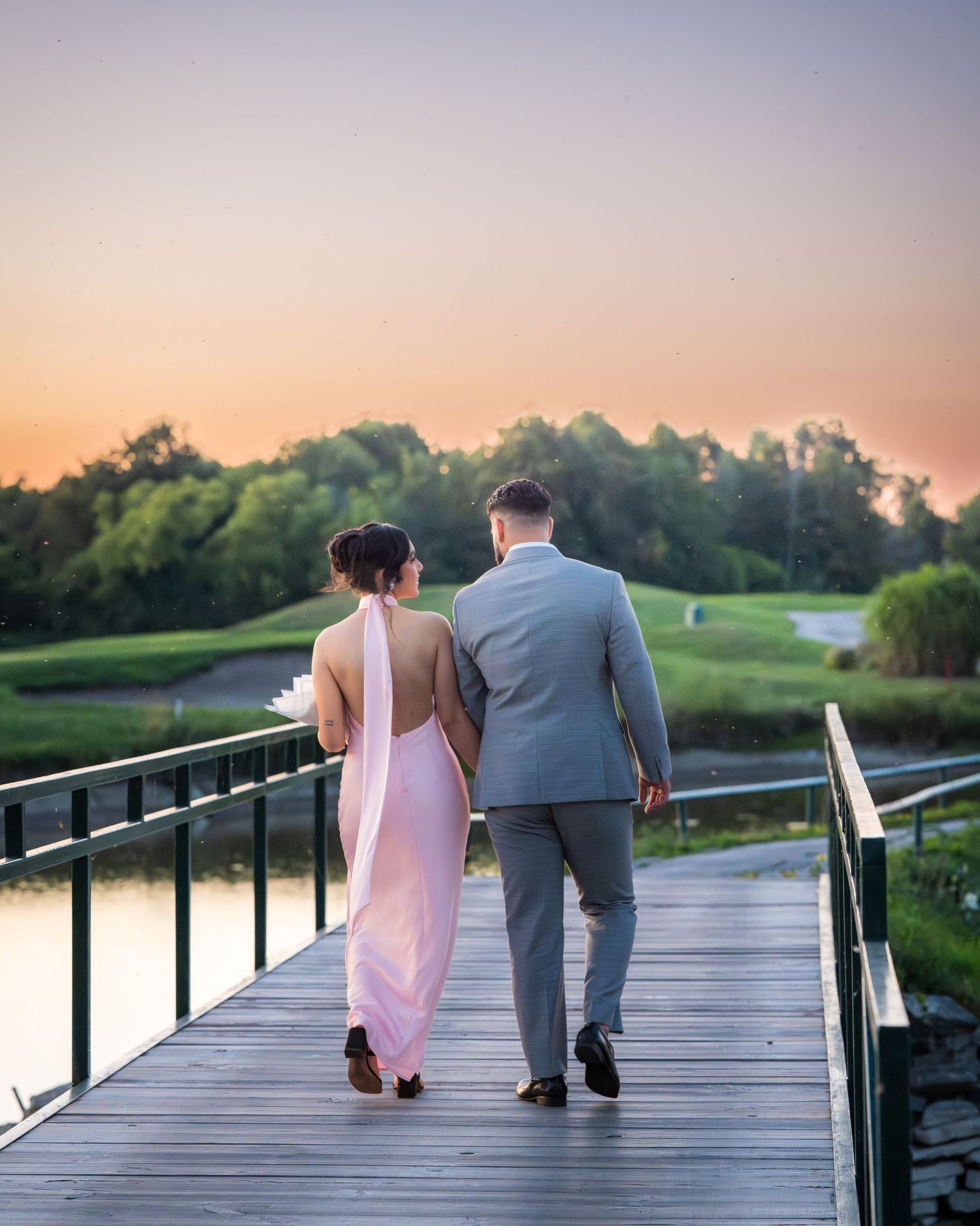 A couple walking away together on a wooden boardwalk during golden hour.