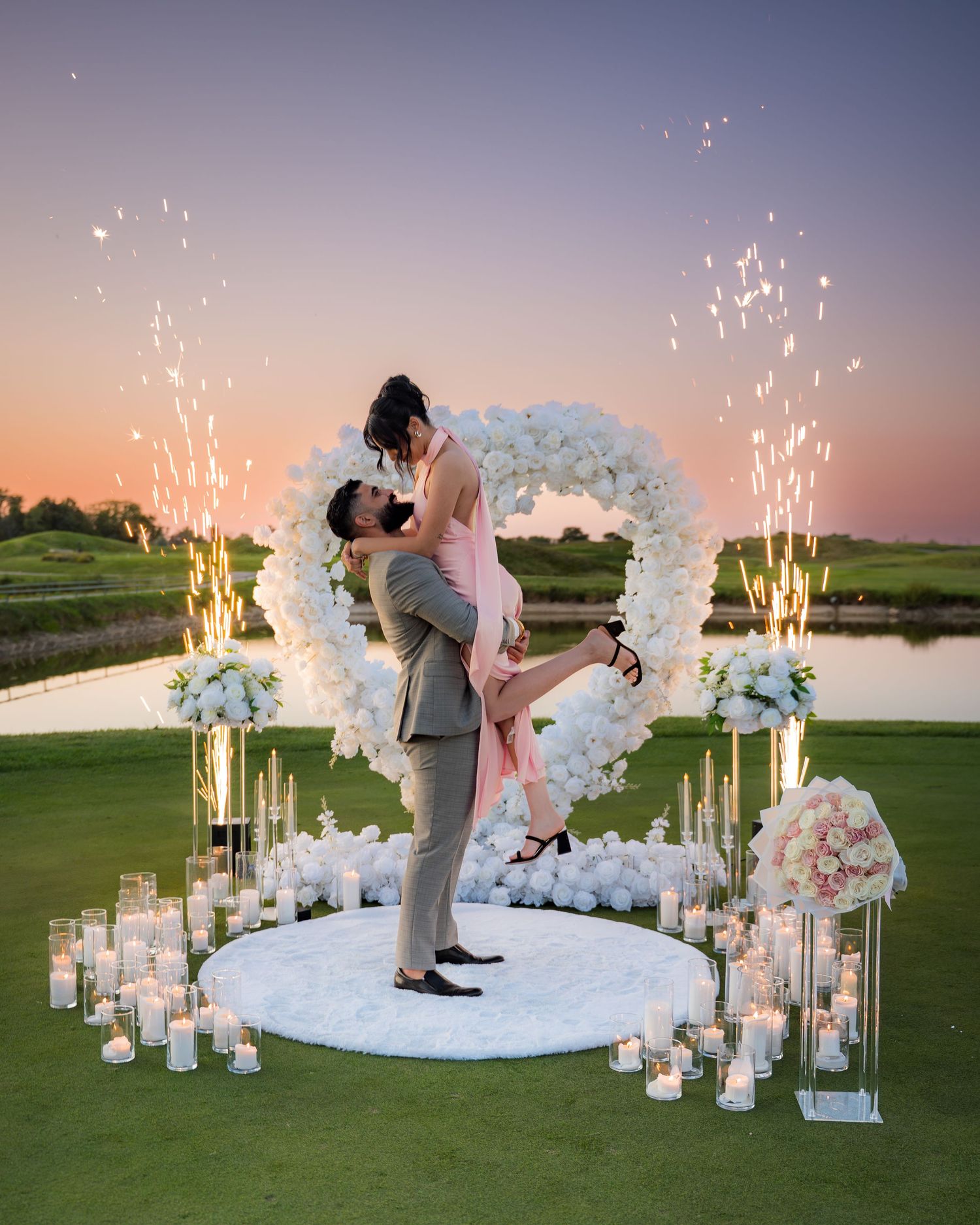 Romantic evening proposal setup with sparklers and floral decorations.
