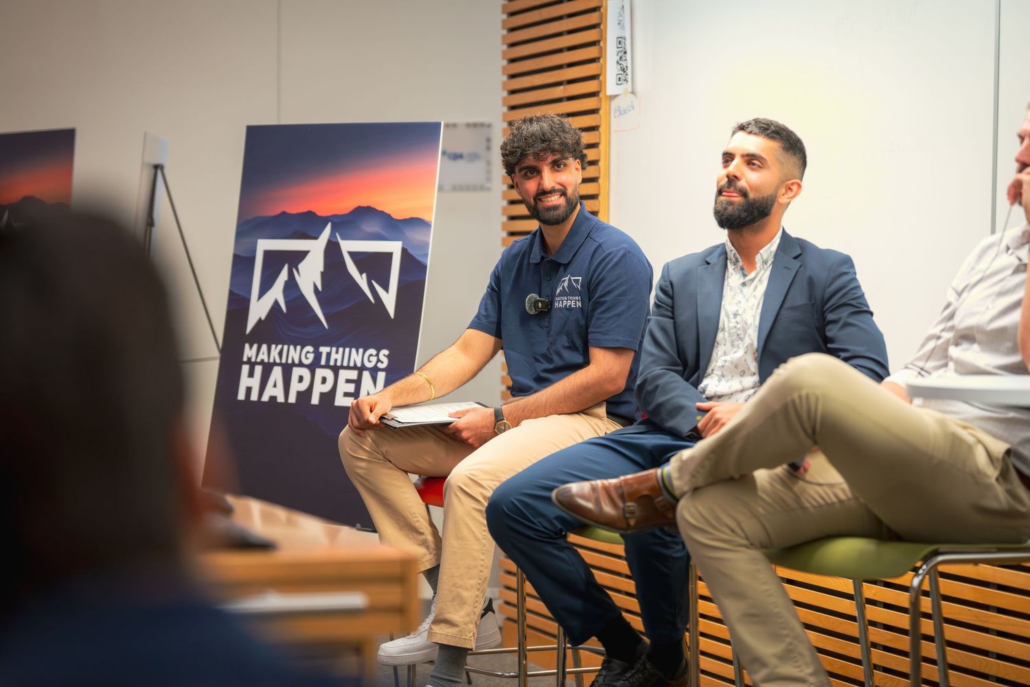 Conference panel with speakers seated against a backdrop showing a mountain logo and 'Making Things Happen' text.