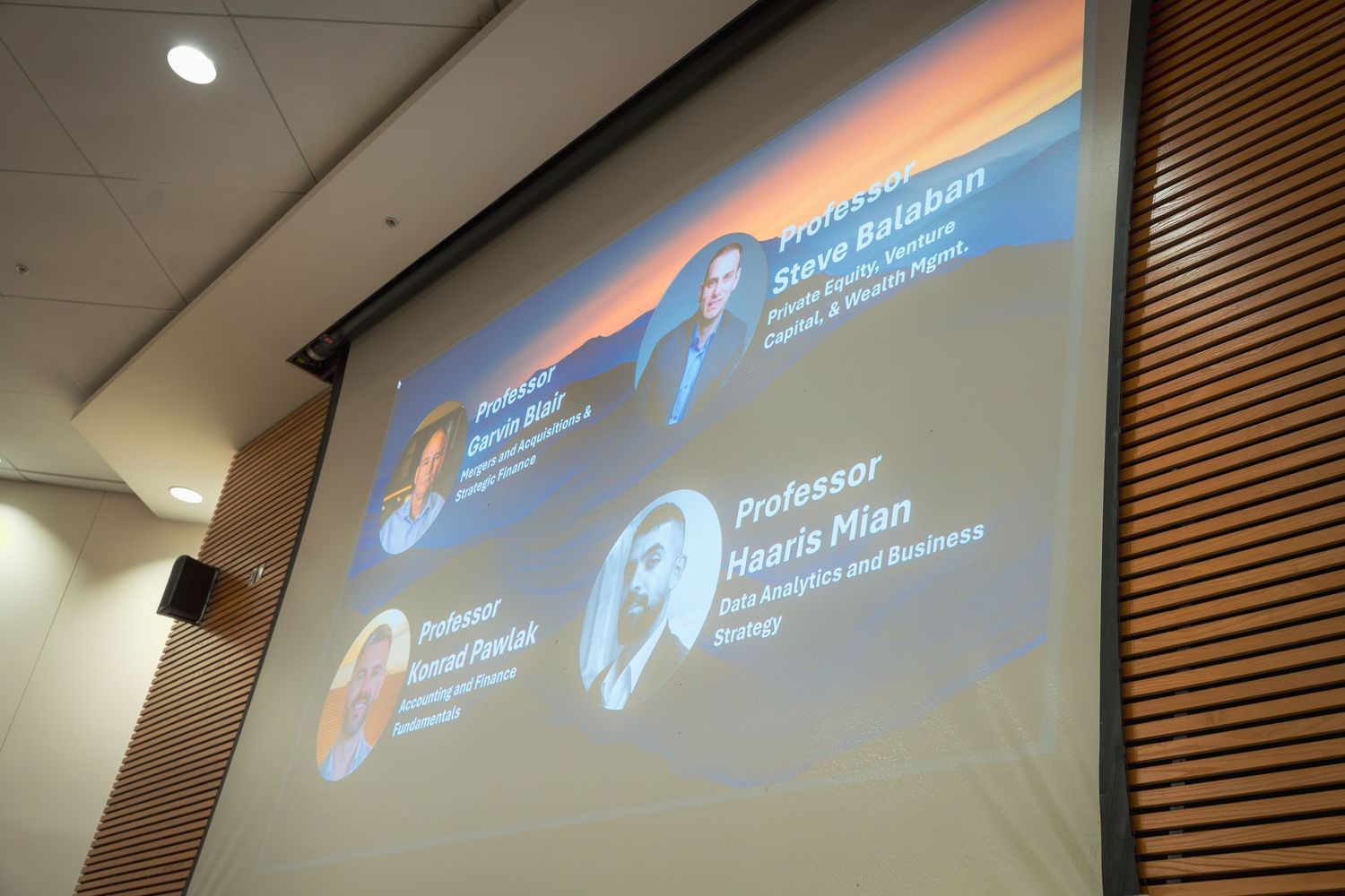Projection screen displaying presentation slides in a dimly lit conference room.