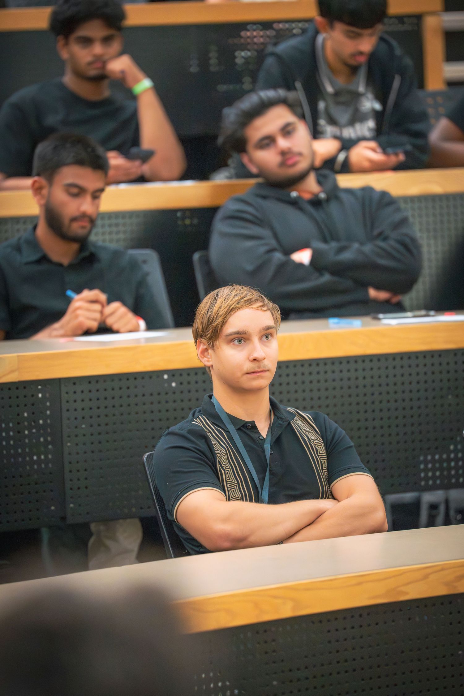 Students seated in curved rows of a modern lecture hall during a presentation.