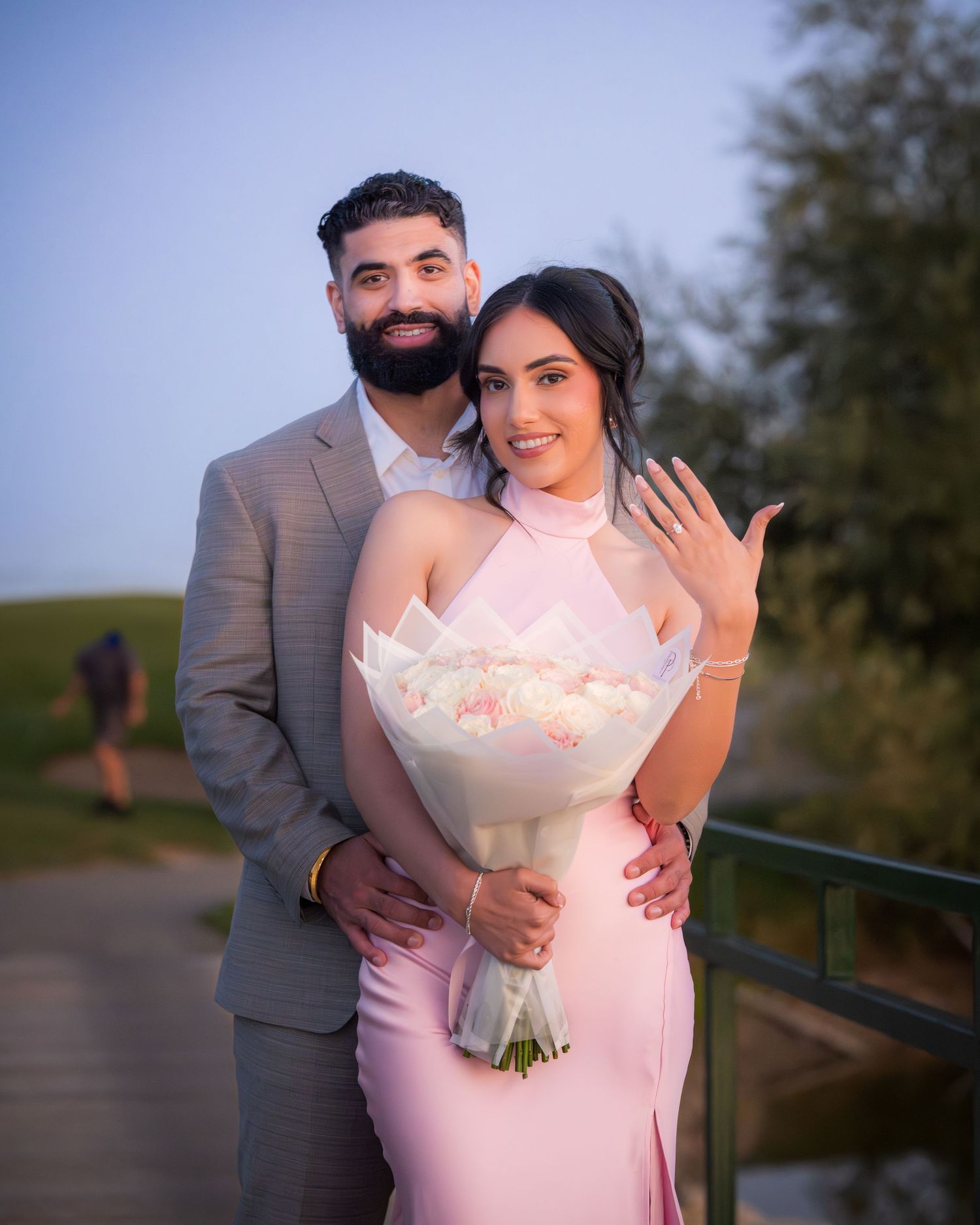 A couple embraces while holding a white bouquet during their outdoor portrait session.