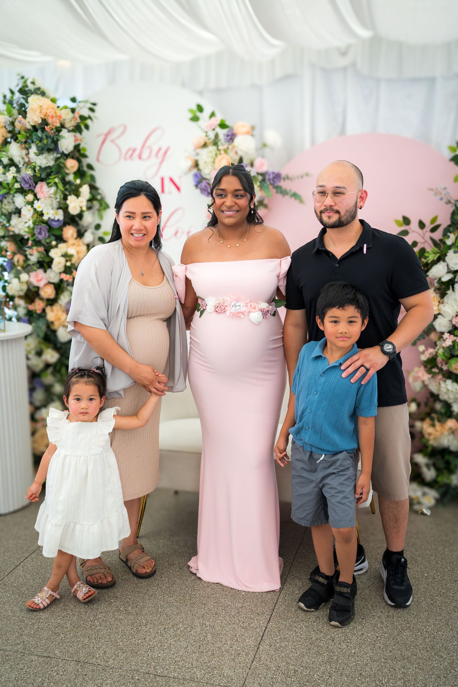 Small family group posing at baby celebration with elegant floral decorations.