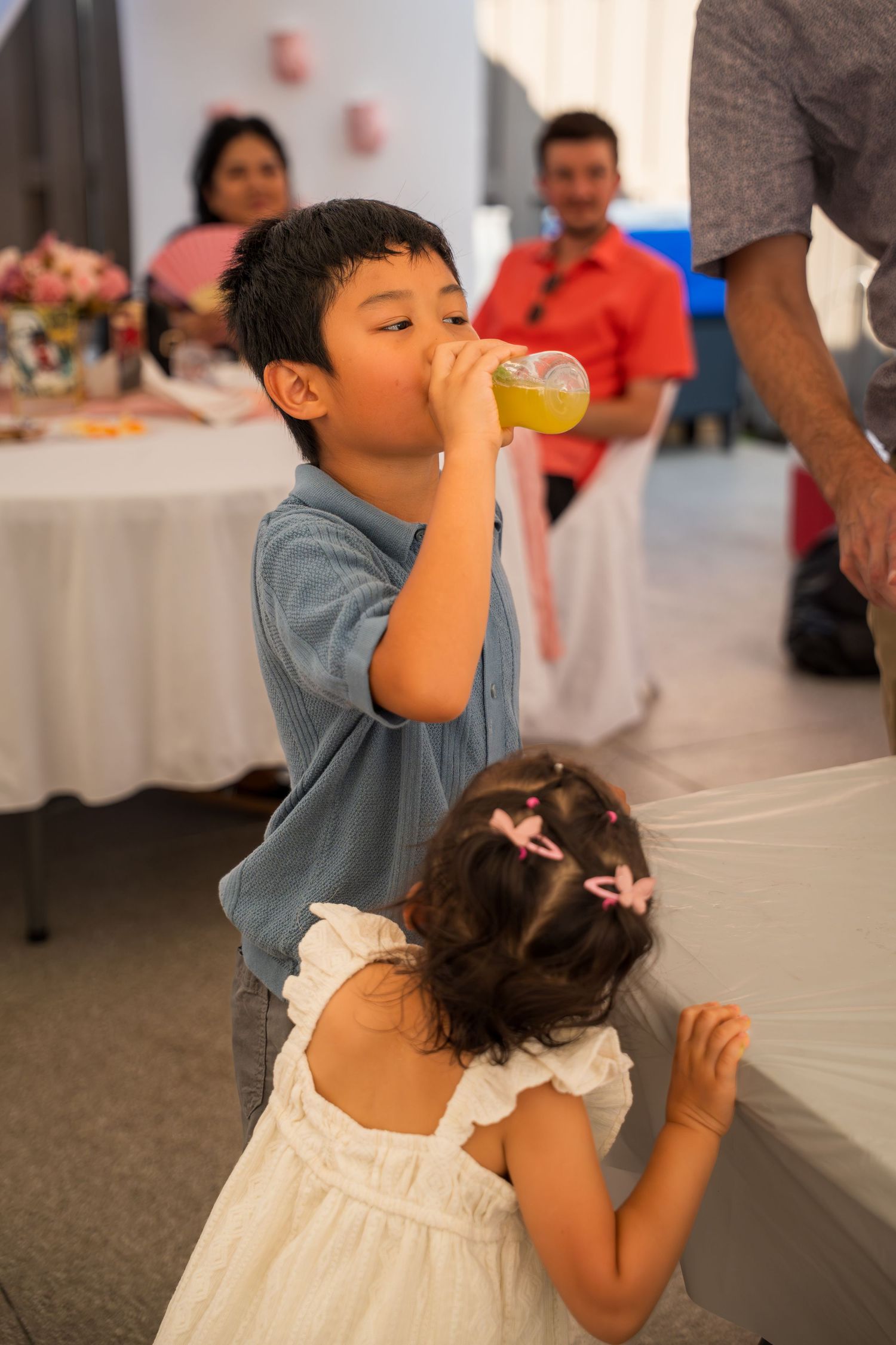 Children drinking beverages at formal event with white tablecloths.