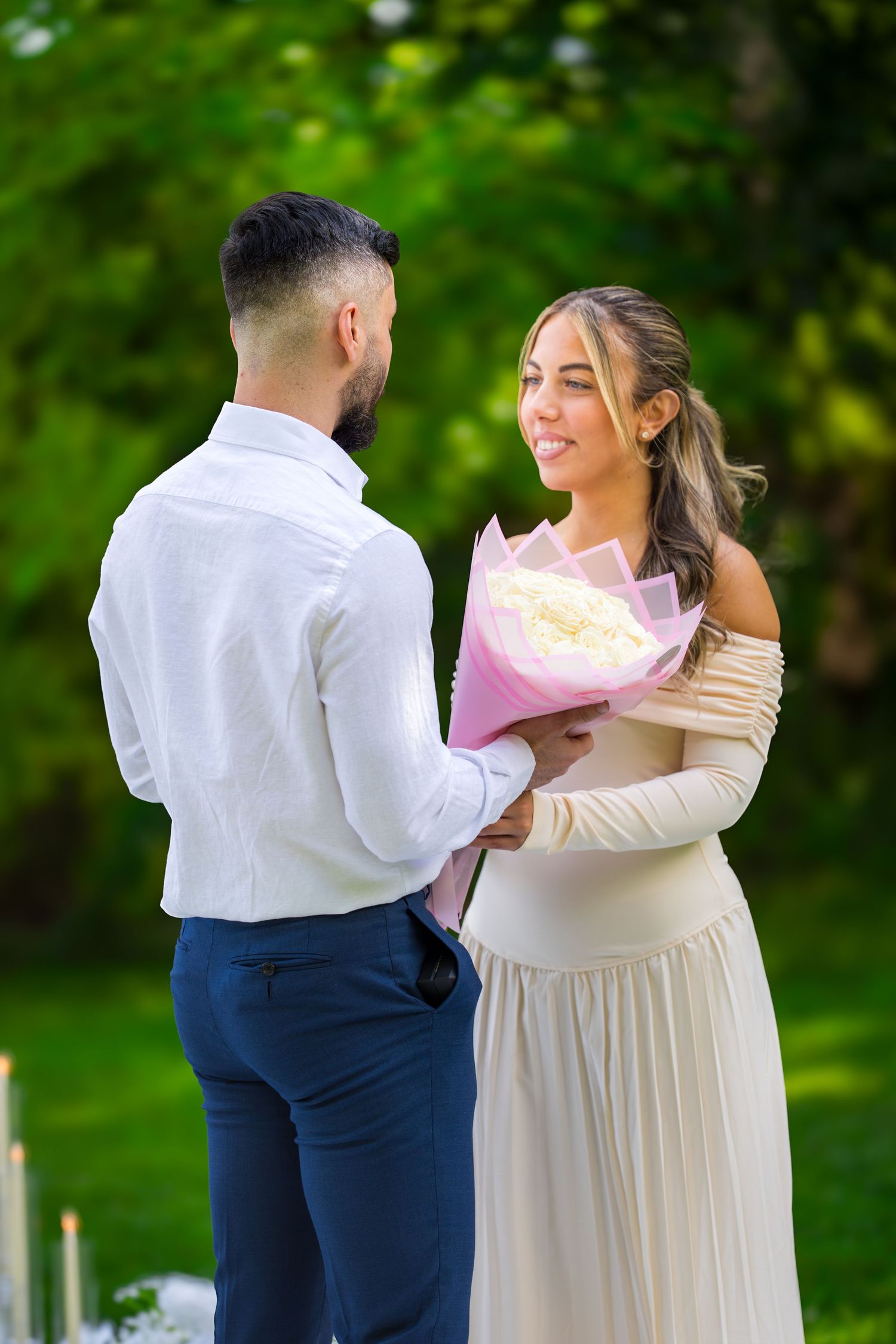 A romantic proposal unfolds in a garden setting with the couple sharing an emotional moment.