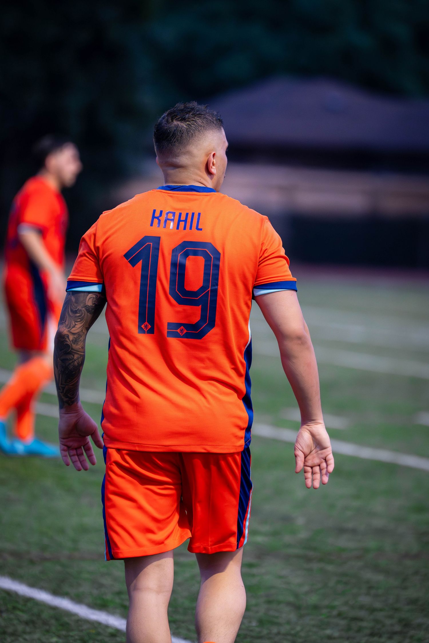 Soccer player in orange jersey with number 19 moves across field during game.