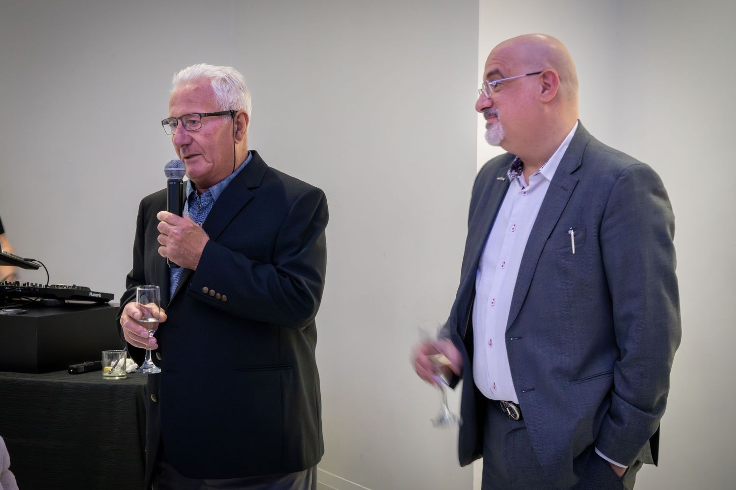 Two men in business attire speaking at a formal event.