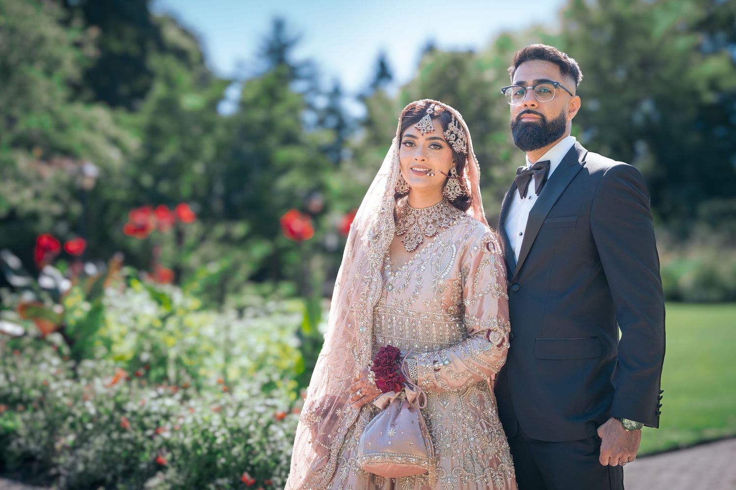Elegant wedding portrait in a lush garden with soft natural lighting and greenery in the background.