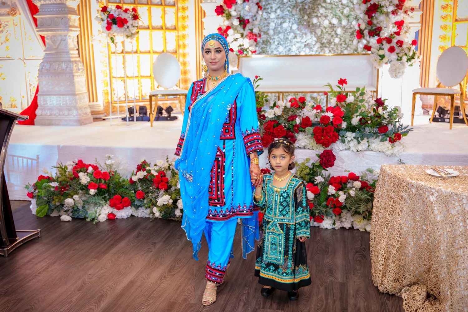 Wedding venue decorated with red roses and golden accents featuring traditional outfits.