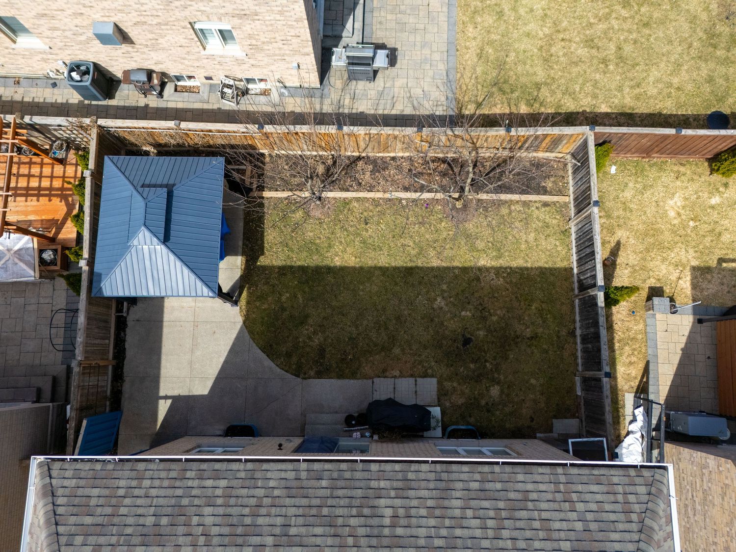 Aerial view of a residential neighborhood showing rooftops, yards, and streets from above on a sunny day.