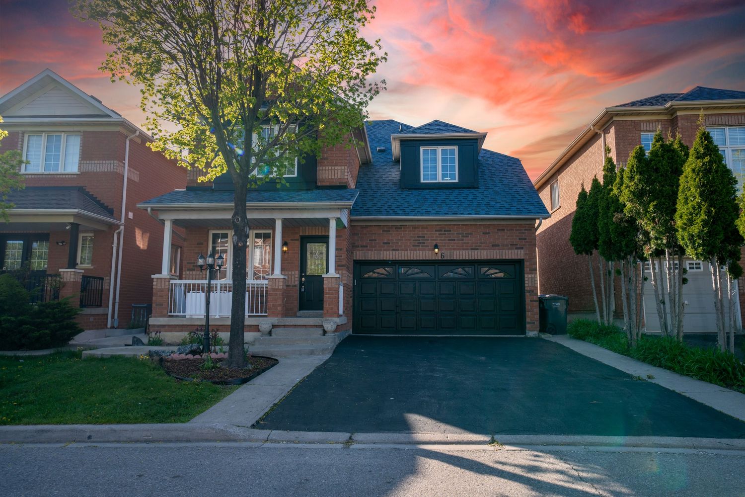 Residential houses with driveways at sunset creating dramatic silhouettes against a vibrant orange and pink sky.